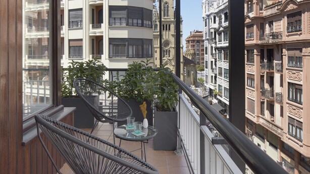 A balcony with wicker chairs, a small table, and potted plants. - Larroka by FeelFree Rentals (San Sebastián)