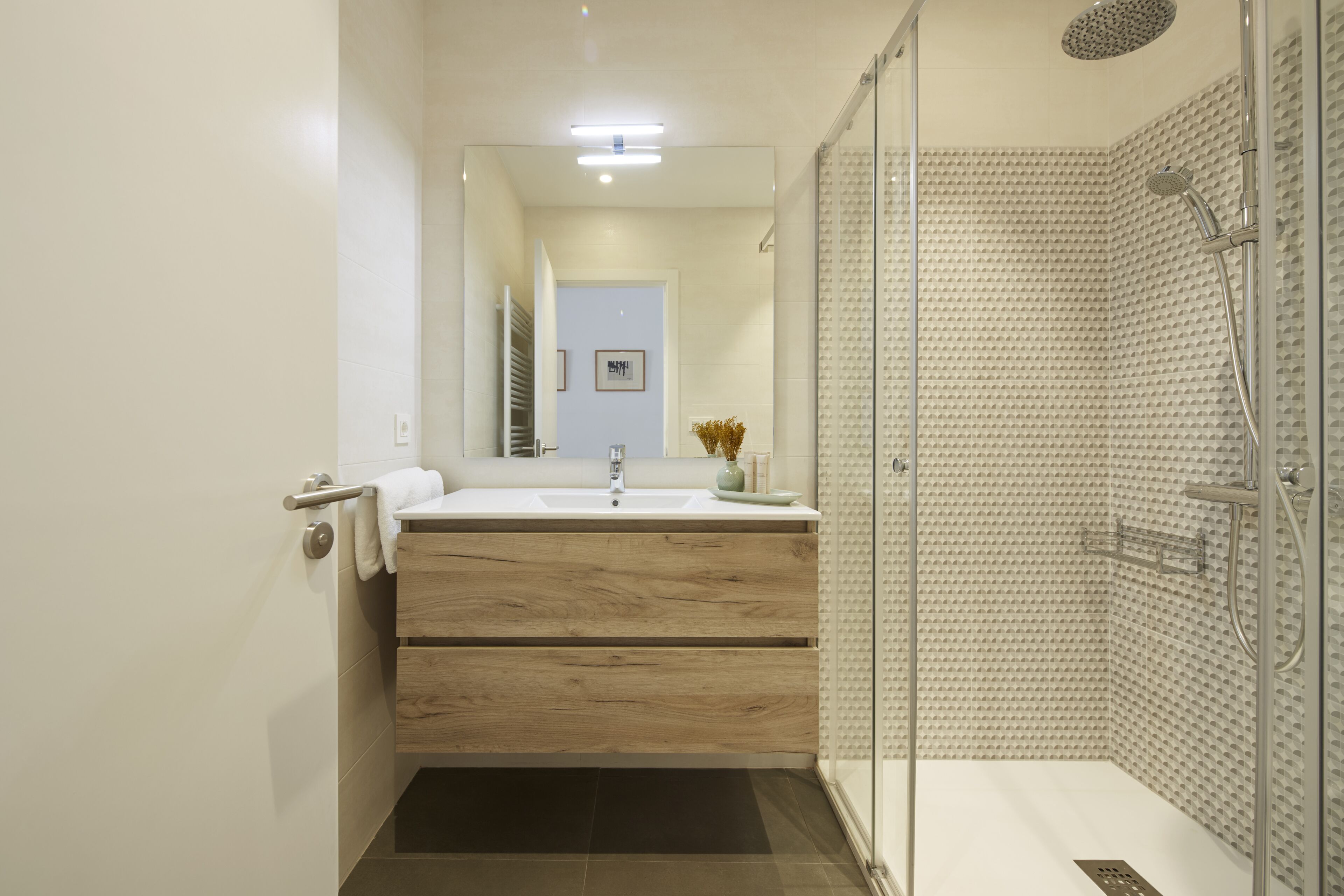 A modern bathroom with a glass-enclosed shower, a wooden vanity, and a white sink.