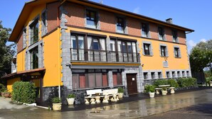 A two-story building with a yellow facade, stone accents, and a balcony with a railing. - Rural house Caserío Ibarrola Txiki for 12 people. (Usurbil)