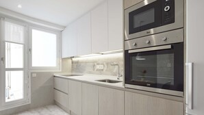 Uma cozinha moderna com eletrodomésticos de aço inoxidável, uma pia dupla e armários em tons claros.