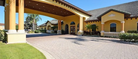 A yellow building with a covered entrance and a paved driveway.