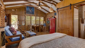 Una habitación acogedora con una cama, un sofá azul, una mesa de comedor y una zona de cocina.