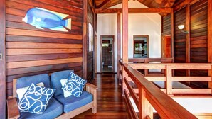 A wooden cabin interior with a sofa and a wooden railing. - Oceanfront treehouse home w/ private pool, deck, near beach (Tola)