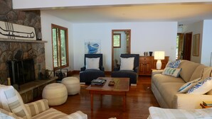 Una sala de estar con chimenea de piedra, dos sillones, un sofá y una mesa de centro.
