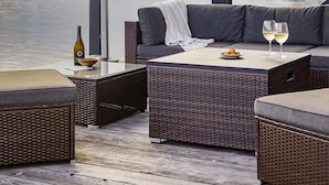 Un área de estar al aire libre con sofá de mimbre, una mesa y una sombrilla.