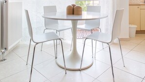 A modern dining area with a round table and four chairs, a radiator, and a hanging light fixture. - Sunny Apartment Steps from Sepolia Metro (Athina)