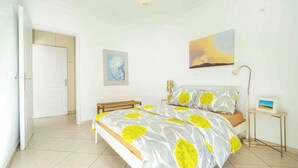 A bedroom with a bed, a bedside table, a lamp, a picture frame, and a door. - Sunny Apartment Steps from Sepolia Metro (Athina)
