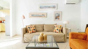 A living room with a beige sofa, a glass coffee table, and a framed picture on the wall. - Sunny Apartment Steps from Sepolia Metro (Athina)