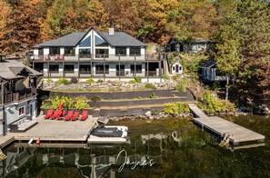A lakeside lodge with a large house, dock, and outdoor seating area. - Priceless views at this 6 bed, 5 bath Cottage + 1 bed Bunkie (Rosseau)