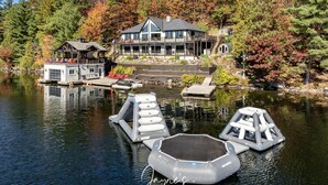 Eine Lodge am Seeufer mit Steg, Schwimmpontons und einem großen Haus mit Balkon.