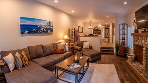 A cozy living room with a sectional sofa, a coffee table, and a fireplace. There is a staircase leading to an upper level. - Fully Stocked & Spacious McCloud 3Bed/ 2.5  Walk to Lake 1-Car Garage (Incline Village)