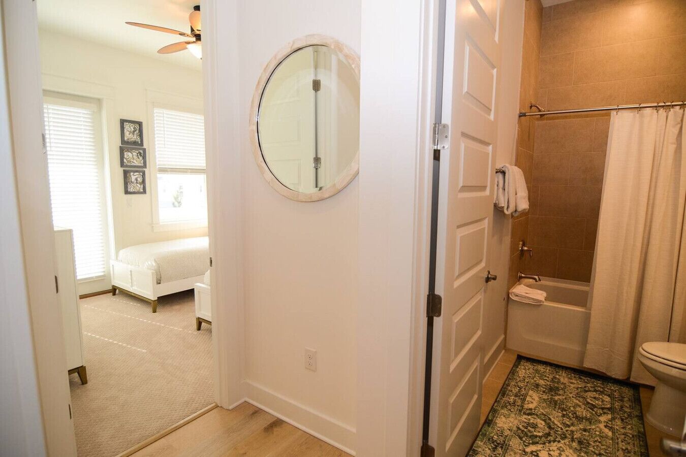 A bathroom with a shower, toilet, and a round mirror.