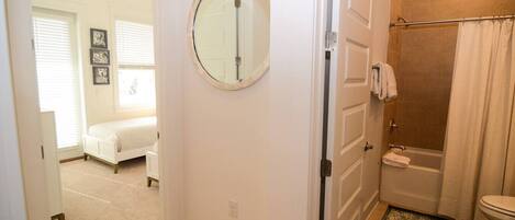 A bathroom with a shower, toilet, and a round mirror.