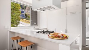A modern kitchen with a central island, a gas stove, and a window overlooking a residential area.
