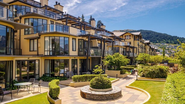 A modern hotel with multiple balconies, outdoor seating, and a well-maintained garden. - Lakefront at 911 The Beacon | Studio (Queenstown)