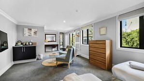 A modern hotel room with a kitchenette, a dining area, a large window with a view, and a cozy seating area. - Lakefront at 911 The Beacon | Studio (Queenstown)