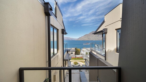 Een smal balkon met uitzicht op een meer en bergen.