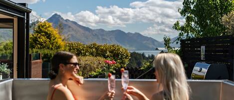 Two people toasting with champagne glasses in a hot tub with a mountain view.