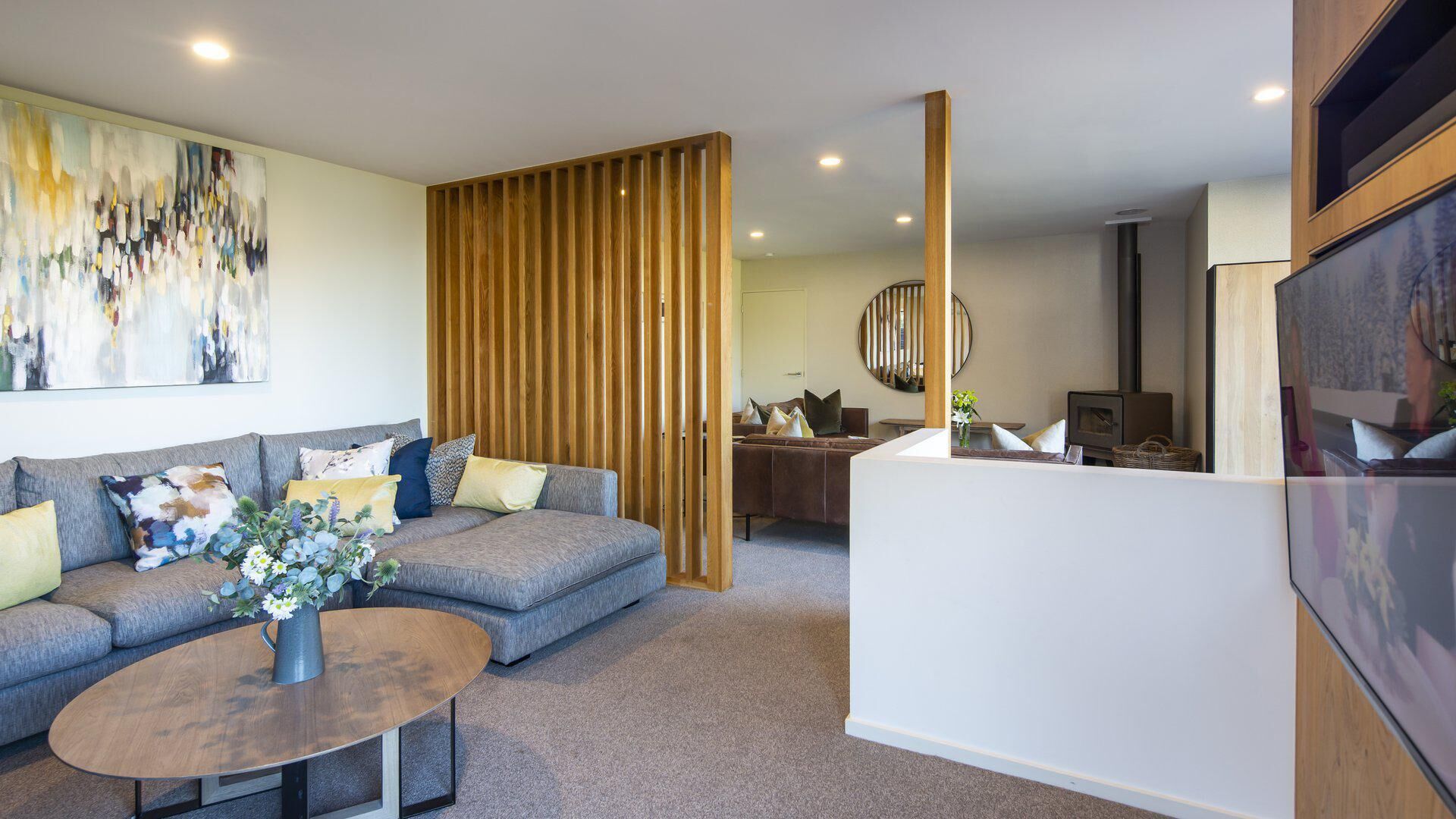 A modern living room with a grey sofa, a wooden partition, and a white reception desk.