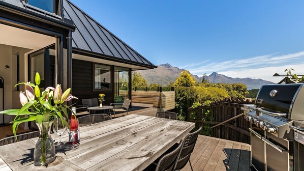 A wooden deck with outdoor furniture, a grill, and a view of mountains. - Mountain Utopia | Entertainers Haven | Spacious with Mountain Lake Views (Queenstown)