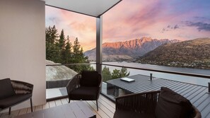 Un balcón con vistas a montañas y un río. Hay dos sillas y una mesa.