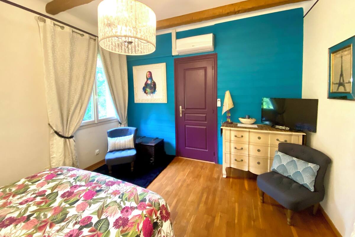 Een slaapkamer met een bed, een stoel, een kaptafel en een televisie.