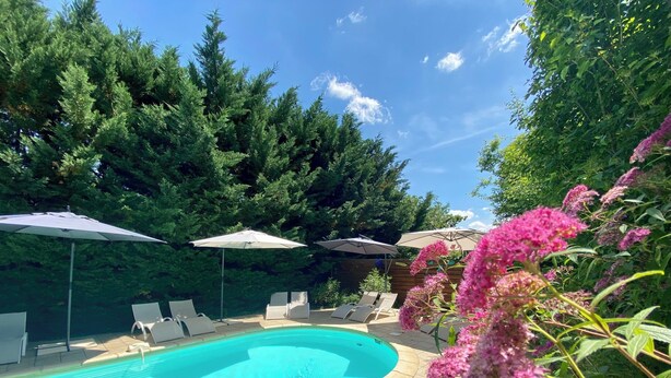 A swimming pool with lounge chairs and umbrellas, surrounded by trees and shrubs. - Ô Clair de Lune - Espace bien être avec Spa - Piscine chauffée (Sarlat-la-Canéda)