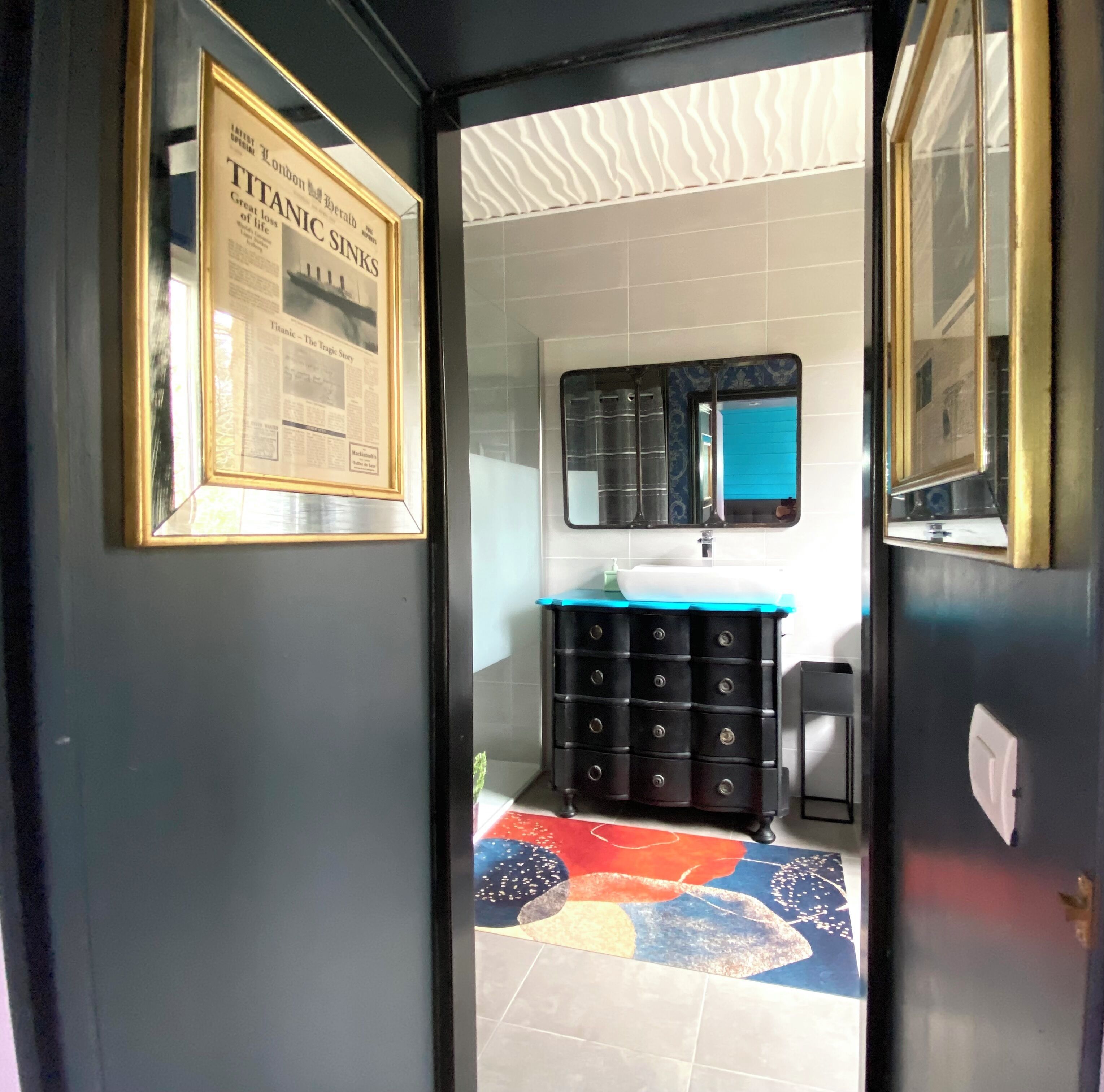 A bathroom with a black cabinet, a sink, and a framed newspaper on the wall.