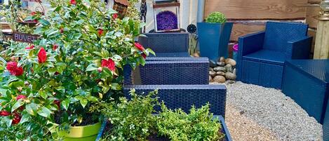 A garden with potted plants, a birdhouse, and a small wooden structure.