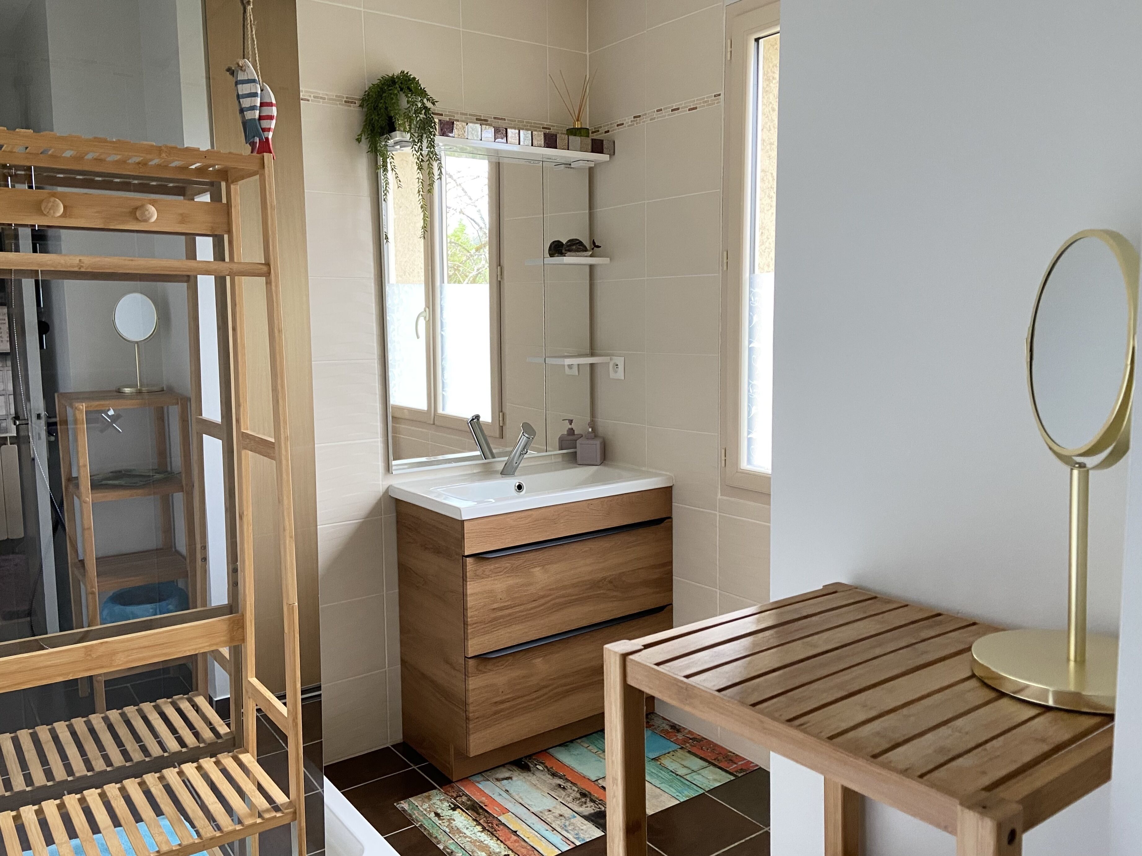 A bathroom with a wooden vanity, a mirror, a sink, and a window.