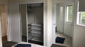 A bedroom with a bed, a closet with shelves, and a window.
