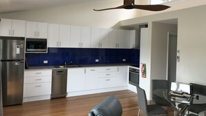A modern kitchen with white cabinets, a built-in oven, and a ceiling fan.