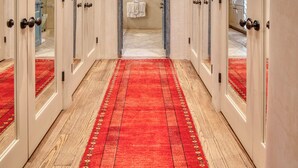 A hallway with wooden floors, a red carpet, and white doors leading to rooms. - Casa Poco Joya | Cozy Santa Fe Gem with Views (Santa Fe)