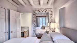 Un dormitorio con dos camas, un espejo grande y decorativo, y vistas a un balcón.
