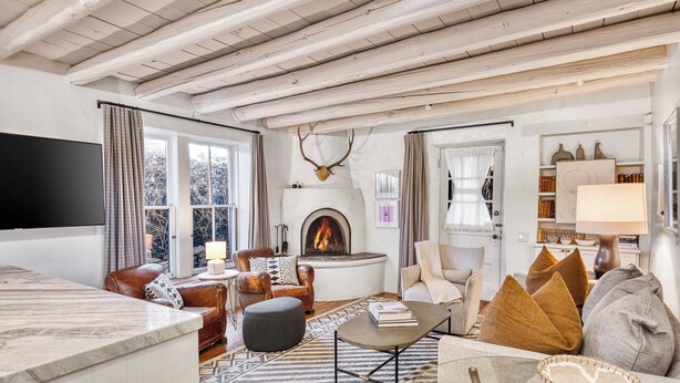 Una sala de estar acogedora con chimenea, sillones de cuero, una mesa de centro y una televisión.