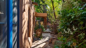 Un sendero de piedra que conduce a una pérgola de madera en un jardín exuberante.