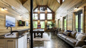A spacious living area with a pool table, a leather sofa, and a dining table with chairs.