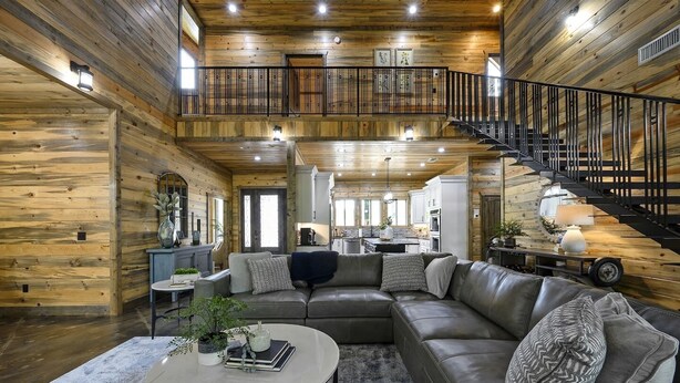 A spacious living room with a leather sofa, a round coffee table, and a staircase leading to an upper level.