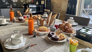 A breakfast setting with a variety of pastries, bread, eggs, and beverages on a table.