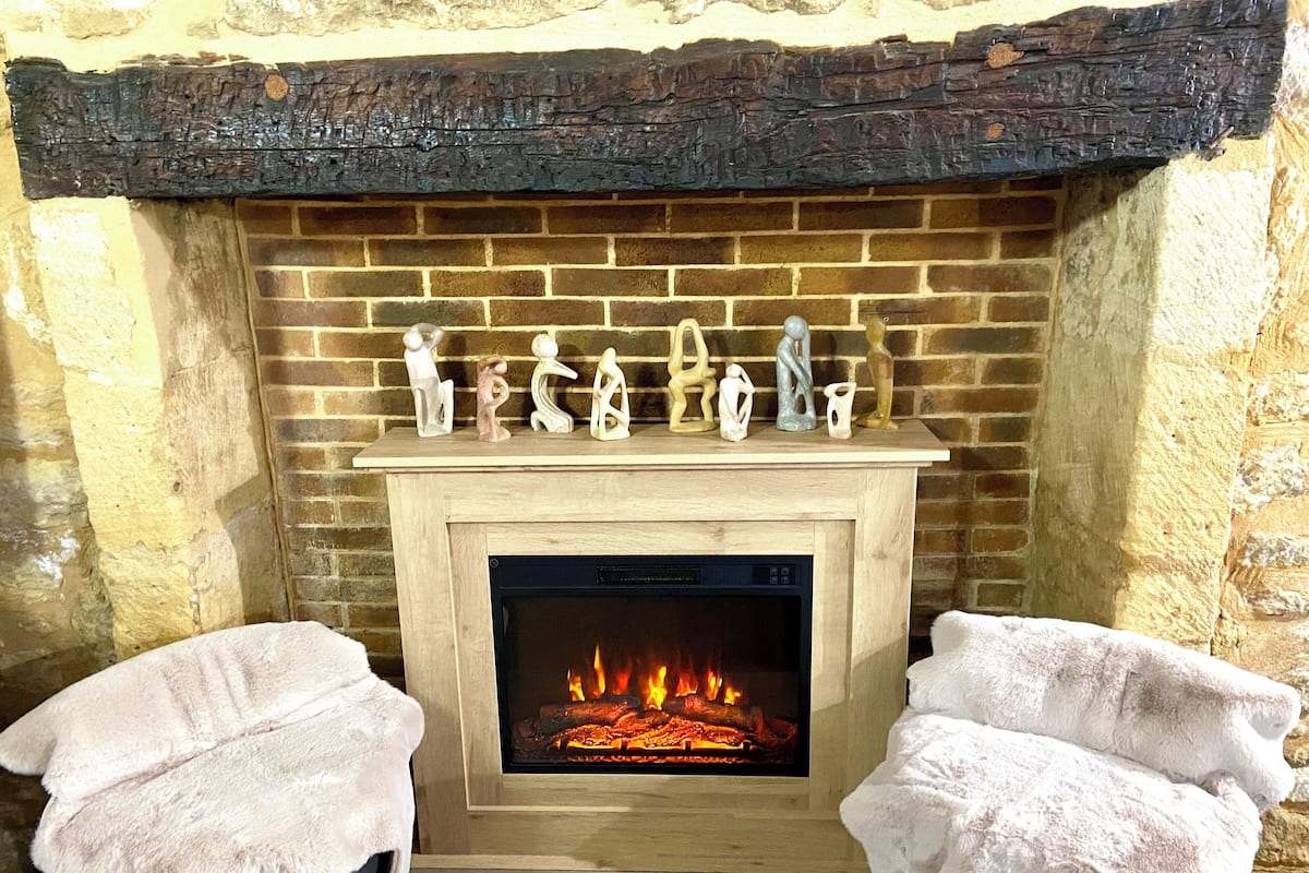 A fireplace with a brick surround and a mantel decorated with various figurines. There are two towels draped over the fireplace.