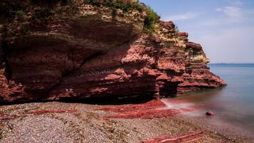 A rocky shoreline with a pebbled beach and a cliff.