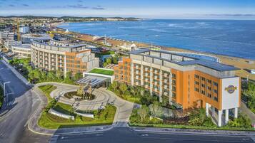 A hotel with a central courtyard, a pool, and a view of the beach and ocean.