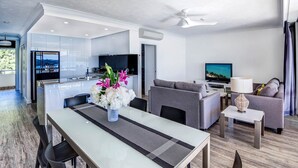 A modern living room with a sofa, TV, and dining area. - Whitsunday Apartment West 1002 (Hamilton Island)