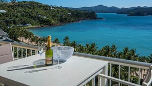 A balcony with a bottle of champagne, a glass, and a table. - Whitsunday Apartment West 1002 (Hamilton Island)