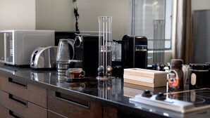 A kitchen counter with a coffee maker, a toaster, a kettle, and a box of tea. - Kimberley House (Cape Town)