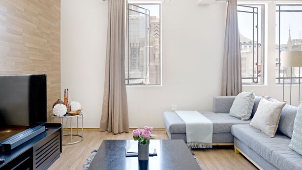 A modern living room with a flat-screen TV, a grey sofa, and a coffee table. - Kimberley House (Cape Town)