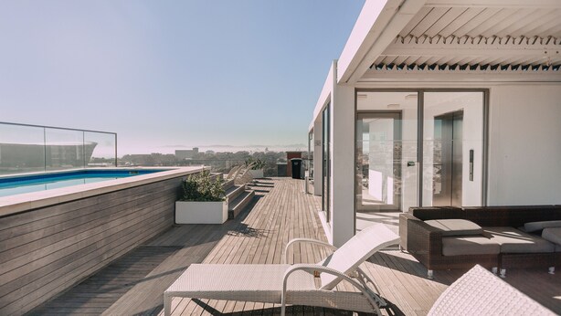 Une terrasse sur le toit avec une piscine, des espaces de détente en plein air et une vue sur le panorama urbain.