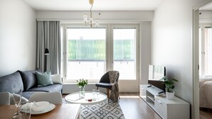 A modern living room with a sofa, a coffee table, a TV, and a dining area with a table and chairs. - SleepWell Apartments Espoo Near Helsinki City Center (Espoo)
