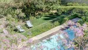 A pool area with a white fence, a chair, and lush greenery. - 438 St Martini (Cape Town)