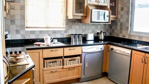 A compact kitchen with wooden cabinets, a microwave, a dishwasher, and a gas stove. - 438 St Martini (Cape Town)